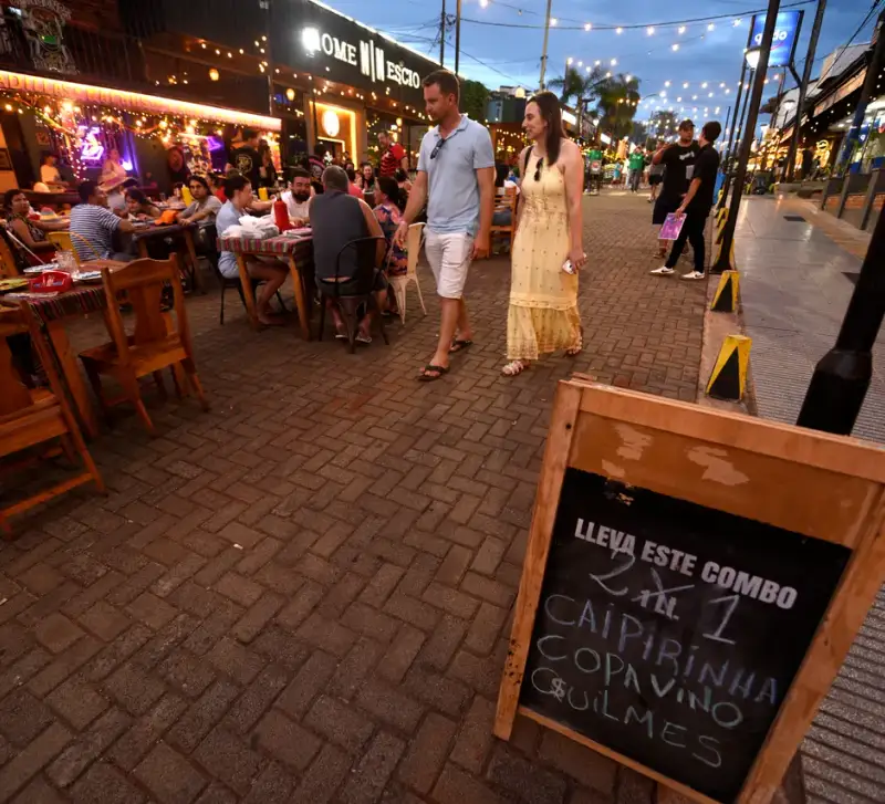 Restaurantes y mesas al aire libre en una calle gastronómica de Iguazú al anochecer