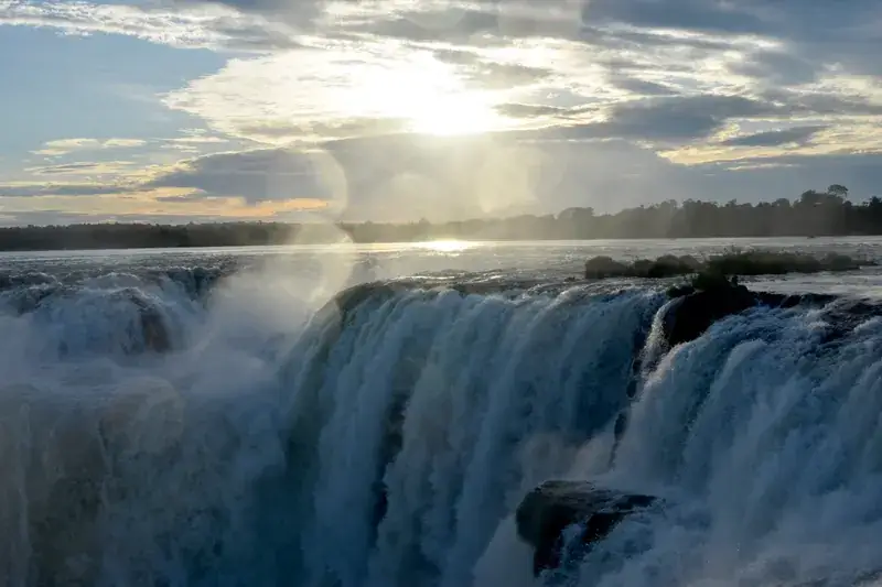 A luz do sol atravessa a névoa sobre as Cataratas do Iguaçu