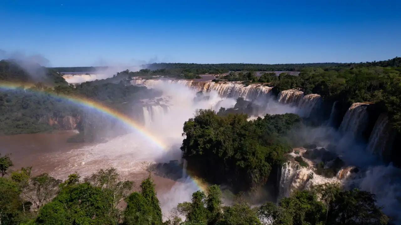 Aerial view of Iguazú Falls with a rainbow above the rainforest